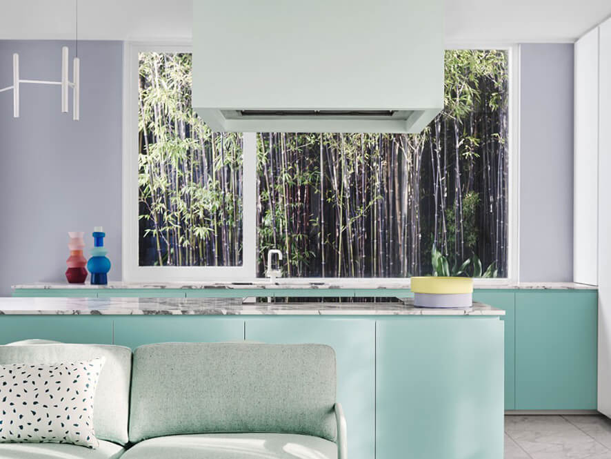 Escapade_soft_green_kitchen_purple_feature_wall_green_couch_marble_countertop_bamboo_window 